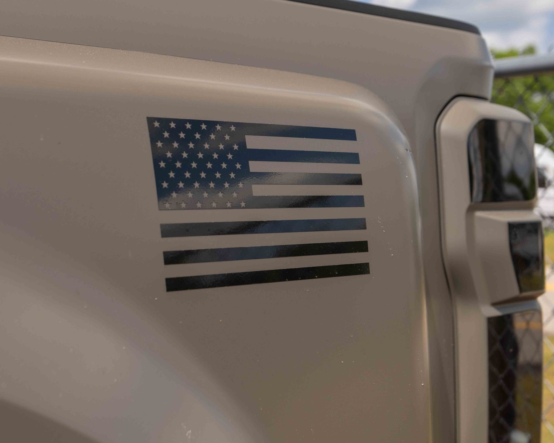 Close-up of a vehicle with an American flag decal on a Marsh gray background.
